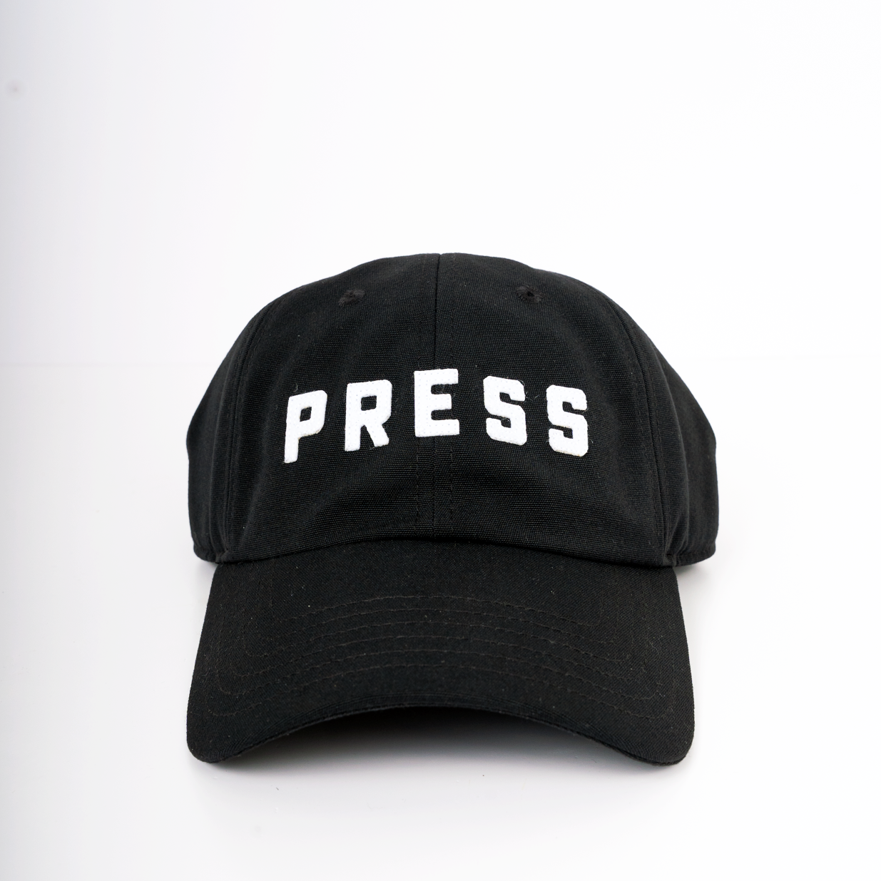 A forward facing view of a PRESS dad hat