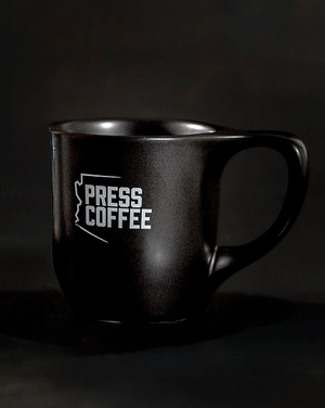 Black mug with 'Press Coffee' logo on a dark background